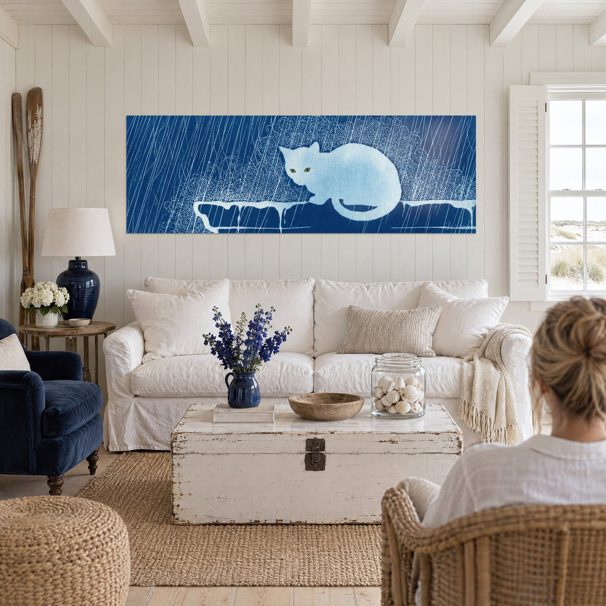 Gemälde Blaugraue Katze mit goldenen Augen unter Regenschlieren, Nachtblau und Weiß, über einem Sofa in einem hellen Wohnzimmer
