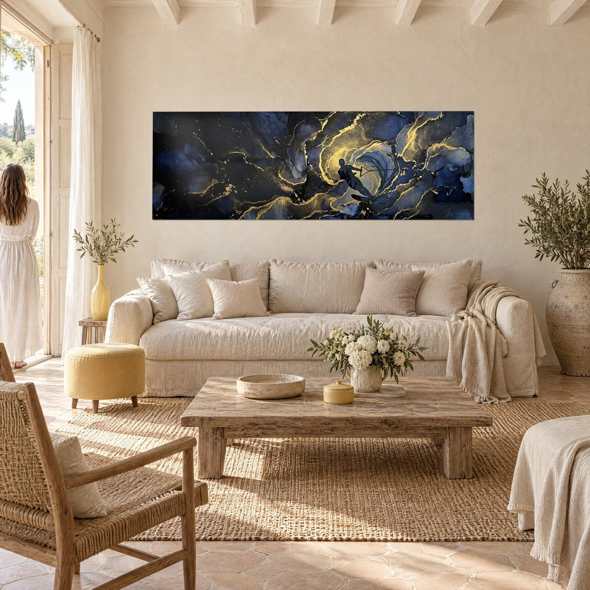 Tableau skieur nautique en silhouette dans une vague bleu nuit veinée d'or, deux femmes de dos, au-dessus d'un canapé dans un salon lumineux