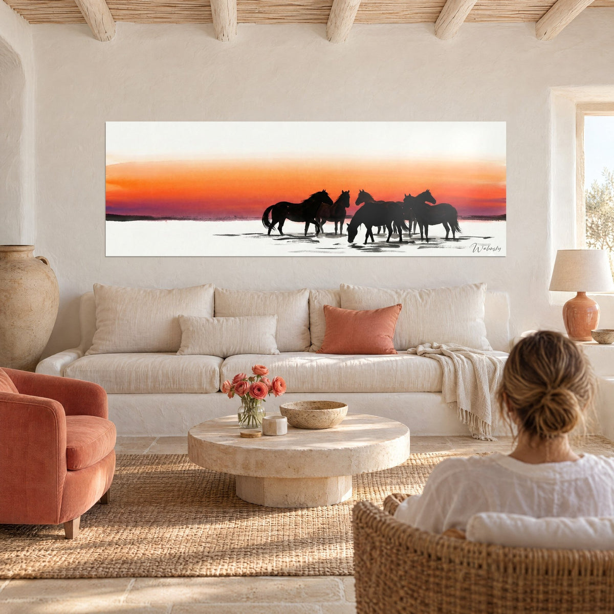 Wall art Camargue horses as black silhouettes against an orange and pink sky, clear pond, above a sofa in a bright living room