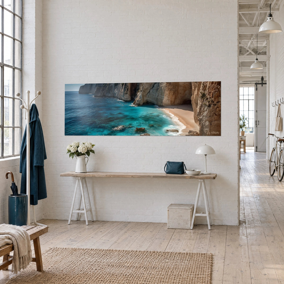 Wall art panoramic view of an azure bay edged with white rocks and beige sand, three-quarter view of a wooden console in the loft