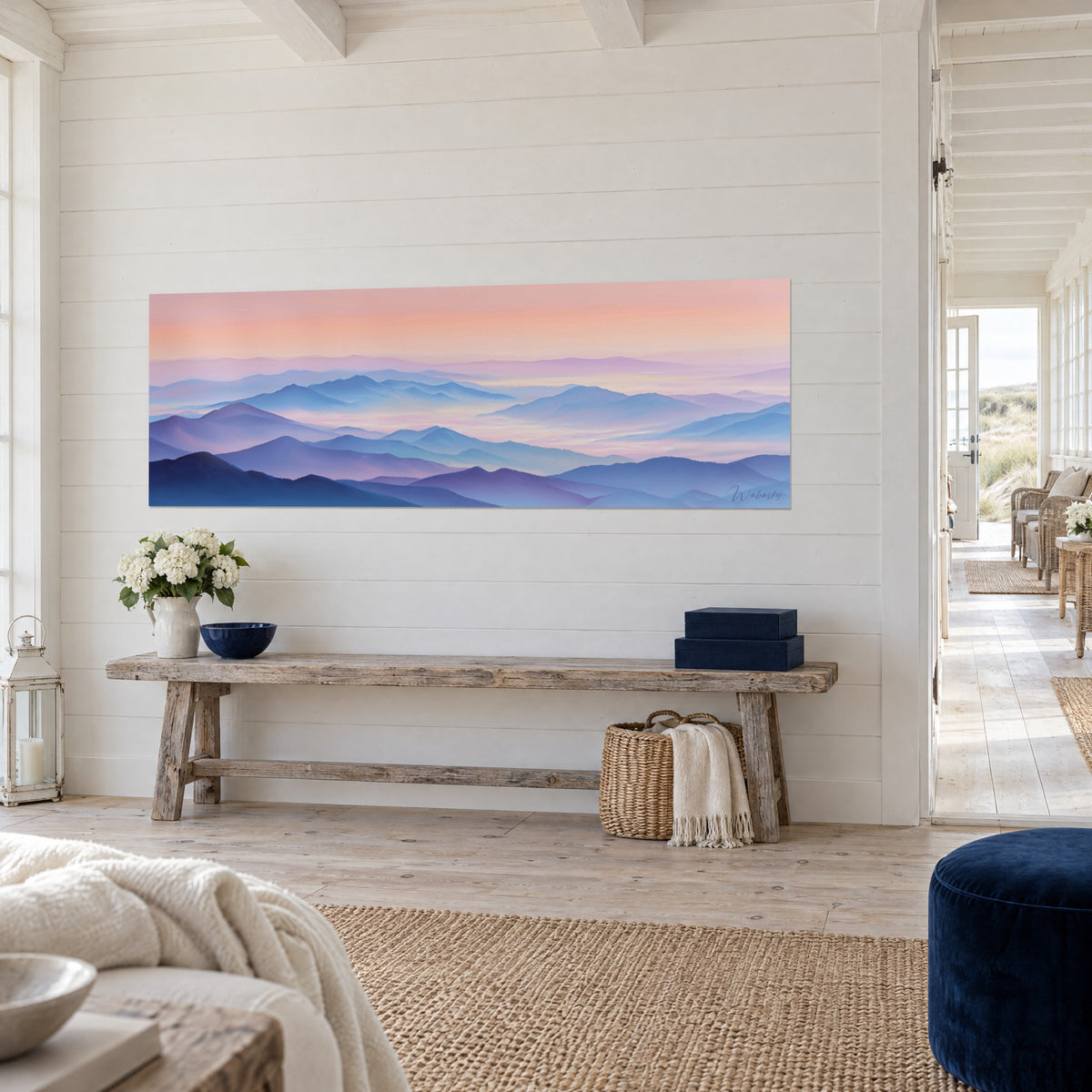 Wall art of a mountain panorama in violet and indigo gradient, sea of pink mist, hung near a wooden console by the seaside