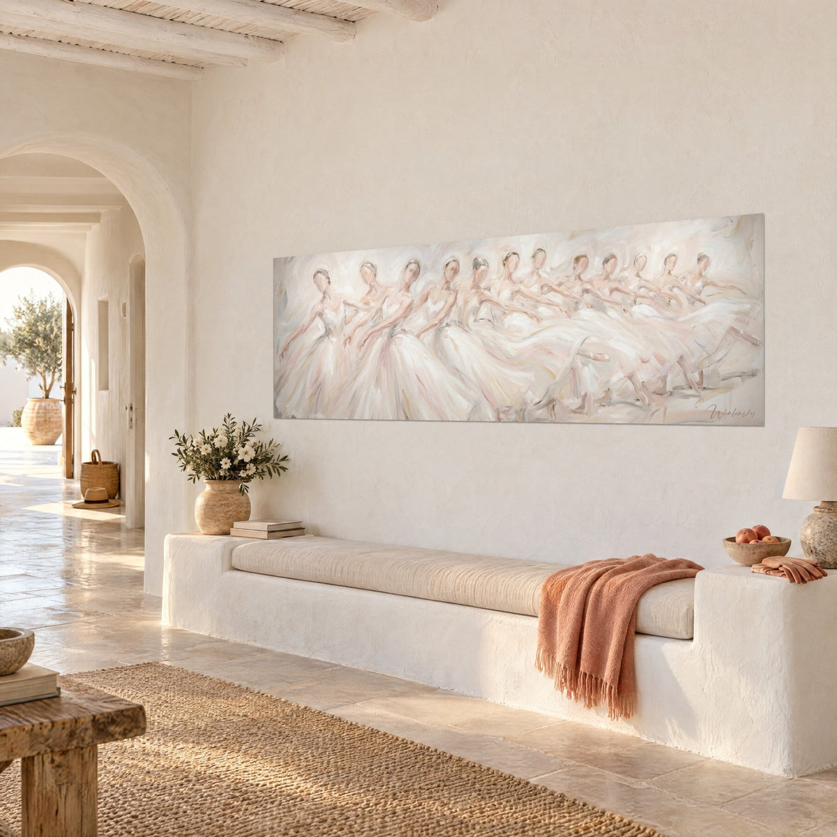 Quadro di corpo di ballo in abiti di tulle color crema e beige rosato, braccia tese in un fregio, davanti al muro imbiancato di una casa mediterranea
