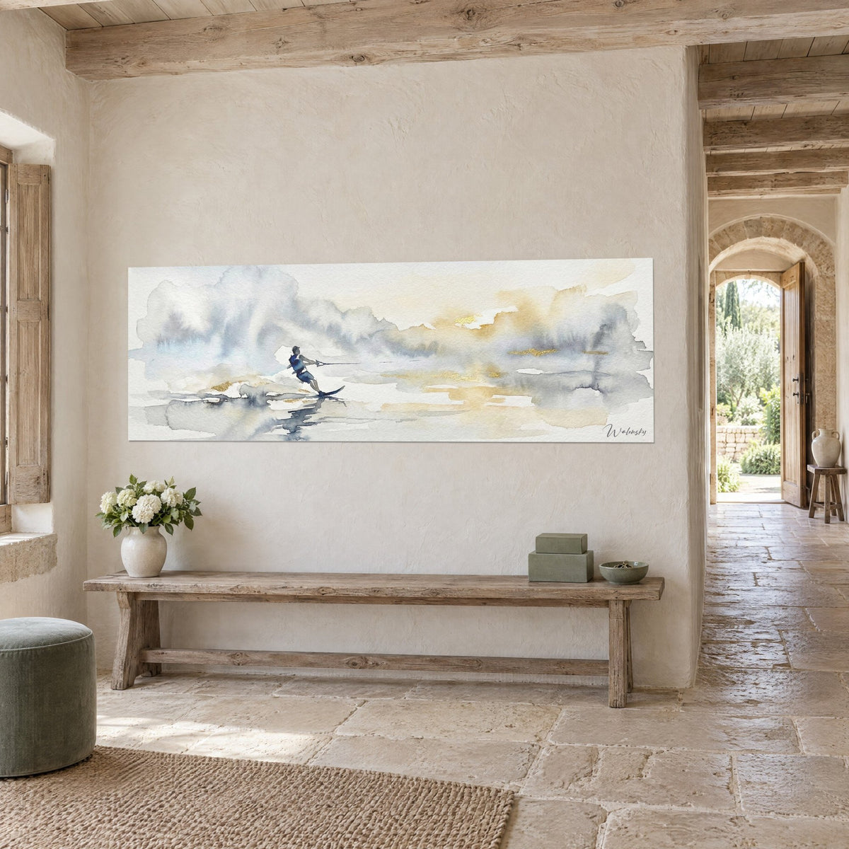 Wall art water skier holding his rope over smooth water, grey-blue clouds and golden glints, stone wall of a country house