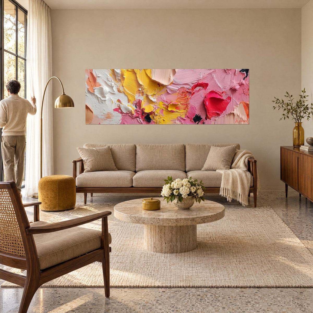 Schilderij met dikke verfimpasto in roze, citroengeel en felrood, van achteren bekeken door een man, boven een bank in een lichte woonkamer