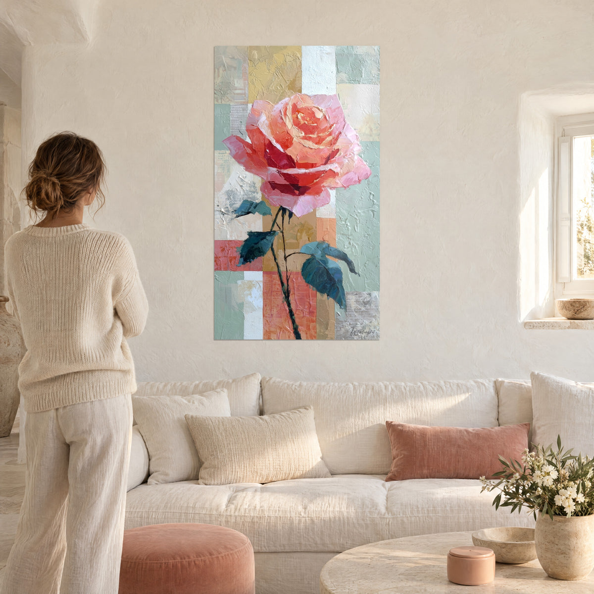 Wall art coral pink flower with impasto petals on a pastel green and ochre mosaic, woman seen from behind, above a sofa in a bright living room