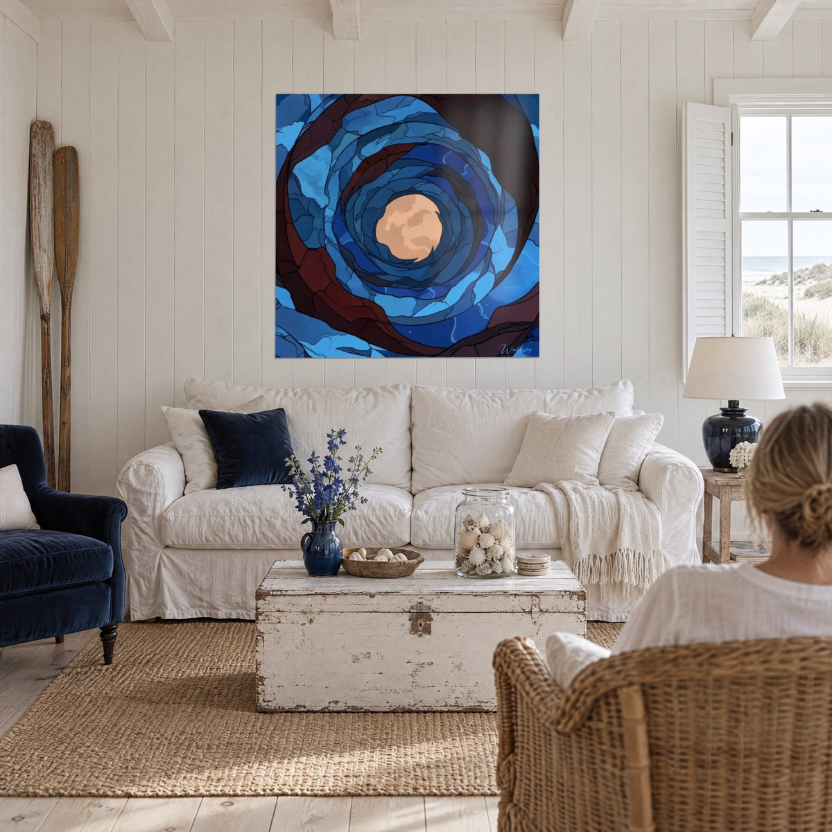 Wall art cosmic spiral in glass, pinkish-beige moon at the centre of blue and burgundy rings, above a sofa in a bright living room
