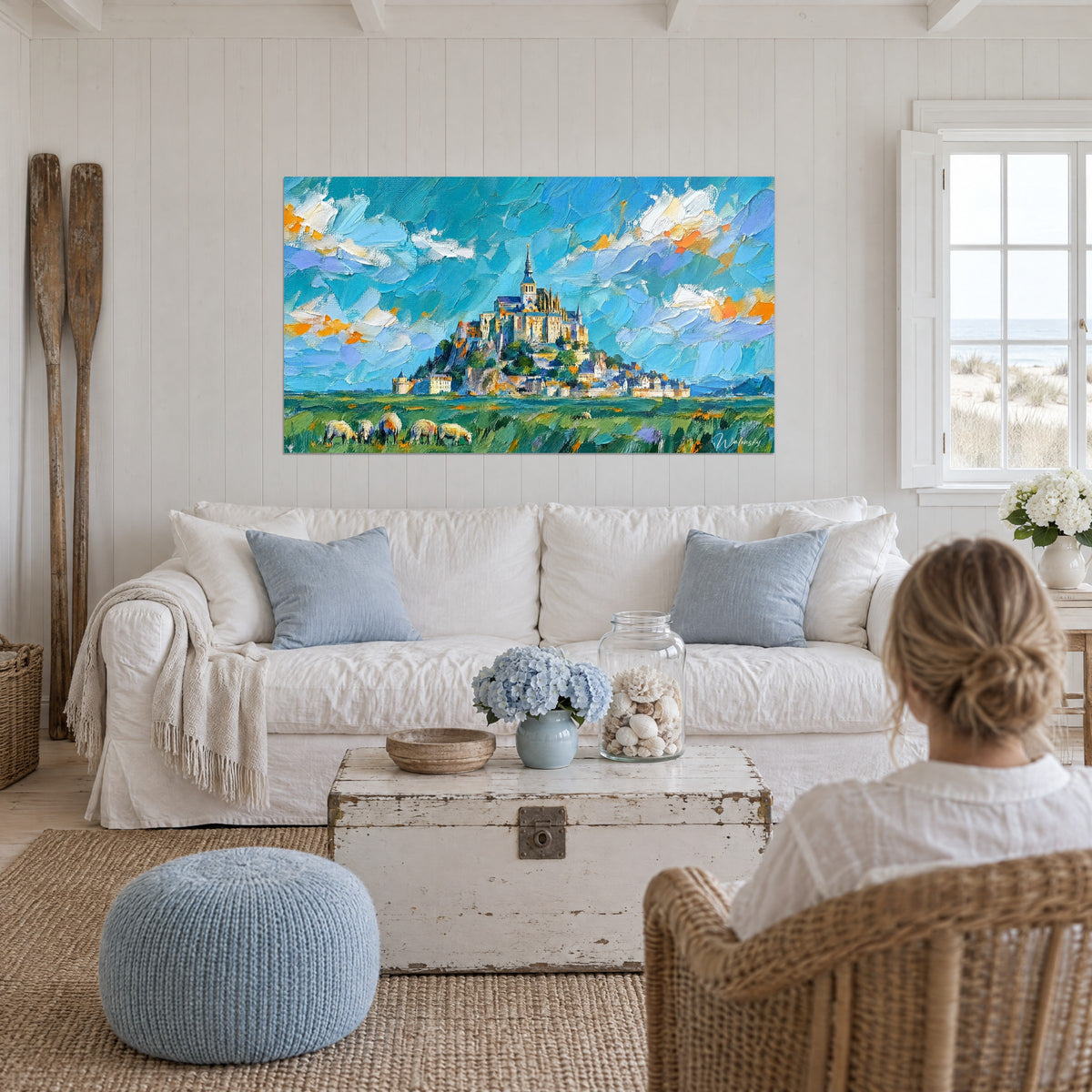 Schilderij van de versterkte abdij op haar rots, turquoise lucht met oranje wolken, boven een bank in een lichte woonkamer