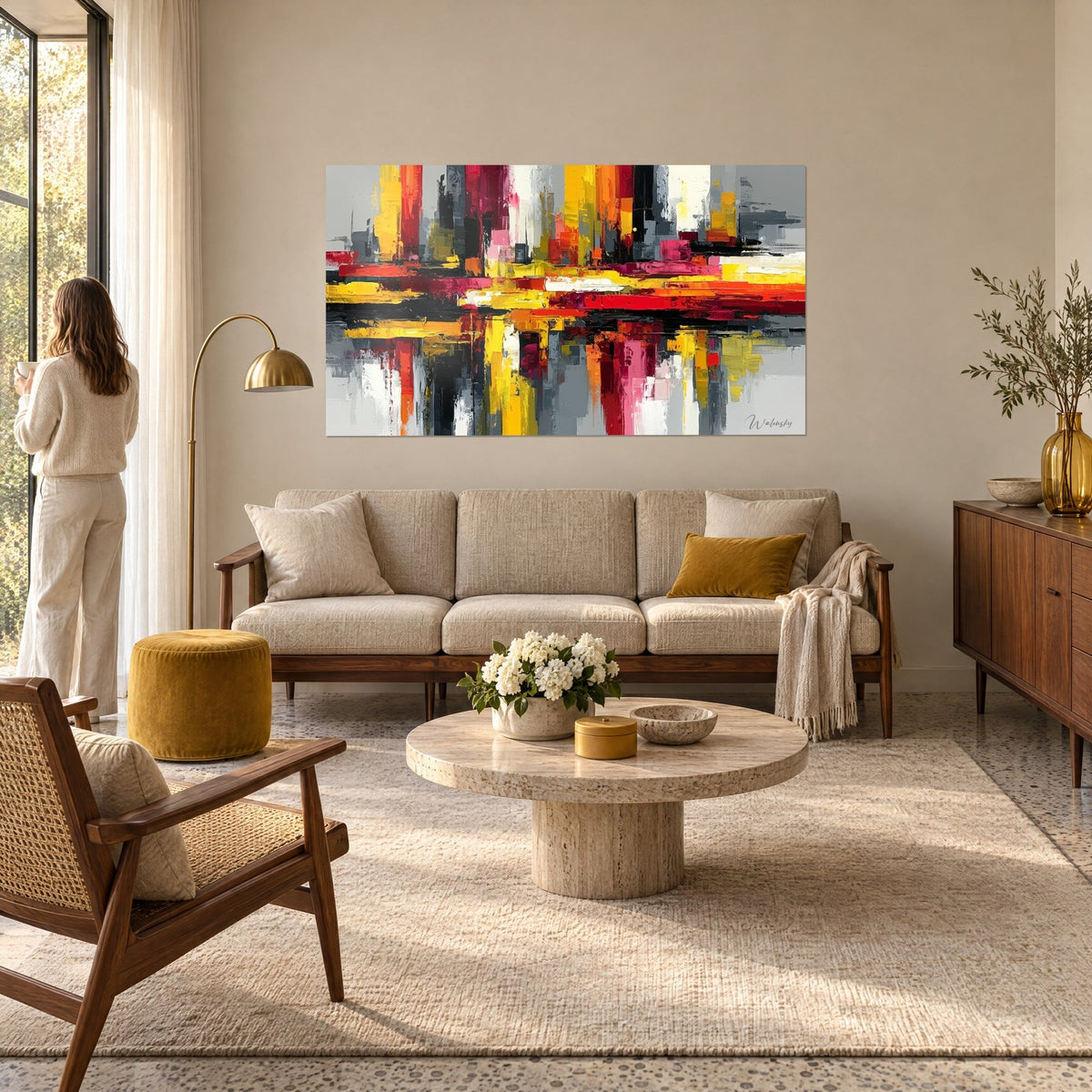 Cuadro de rascacielos abstractos en franjas amarillo mostaza y rojo vivo, goteos sobre fondo gris, encima de un sofá en un salón luminoso