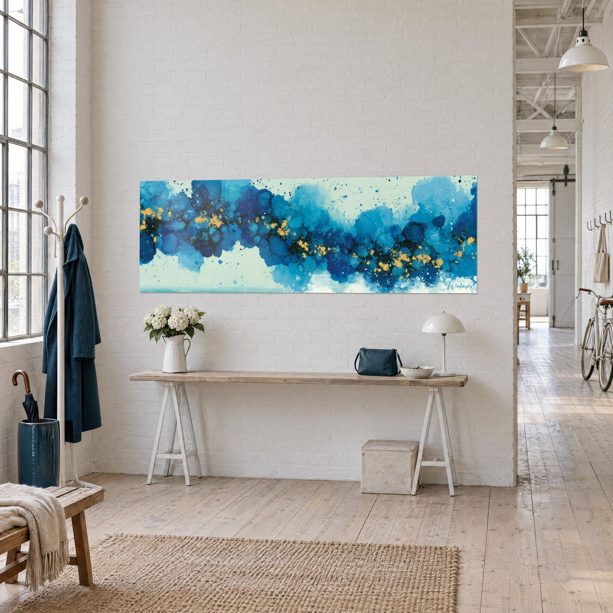 Tableau voûte céleste abstraite, taches d'encre indigo et cyan semées de paillettes ocre, accrochée au-dessus d'une console en bois, loft