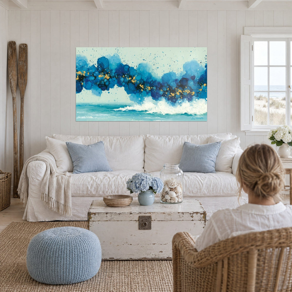 Tableau vague turquoise et bleu cobalt, éclaboussures d'or et écume blanche, au-dessus d'un canapé dans un salon lumineux