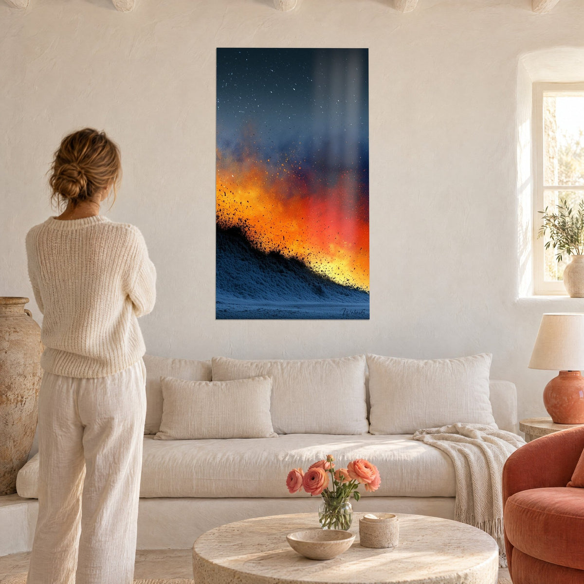 Cuadro erupción incandescente de brasas naranjas y rojas sobre una cresta azul noche, mujer de espaldas, encima de un sofá en un salón luminoso