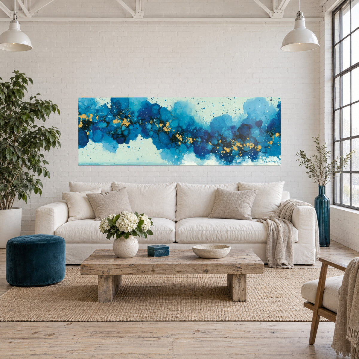 Tableau nébuleuse bleue parsemée d'éclats dorés, nuages d'encre turquoise et marine sur fond vert pâle, au-dessus d'un canapé dans un salon lumineux