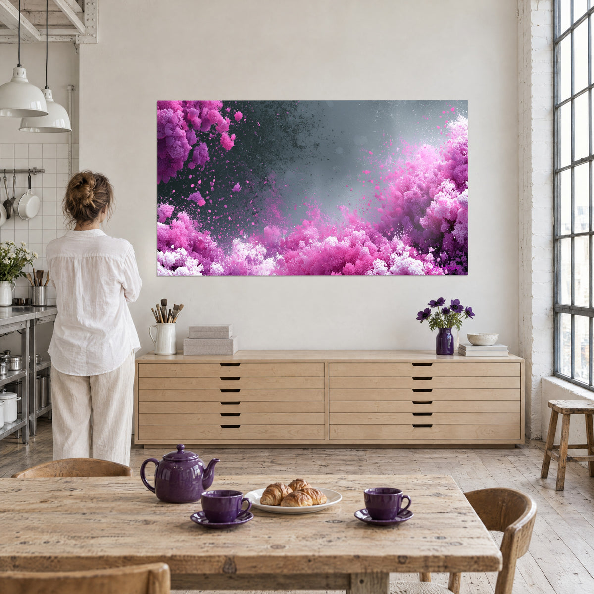 Gemälde mit einer Fontäne aus bonbonrosa und violettem Pulver, graue Dunstschwaden in der Mitte, betrachtet von einer Frau in einem Künstleratelier