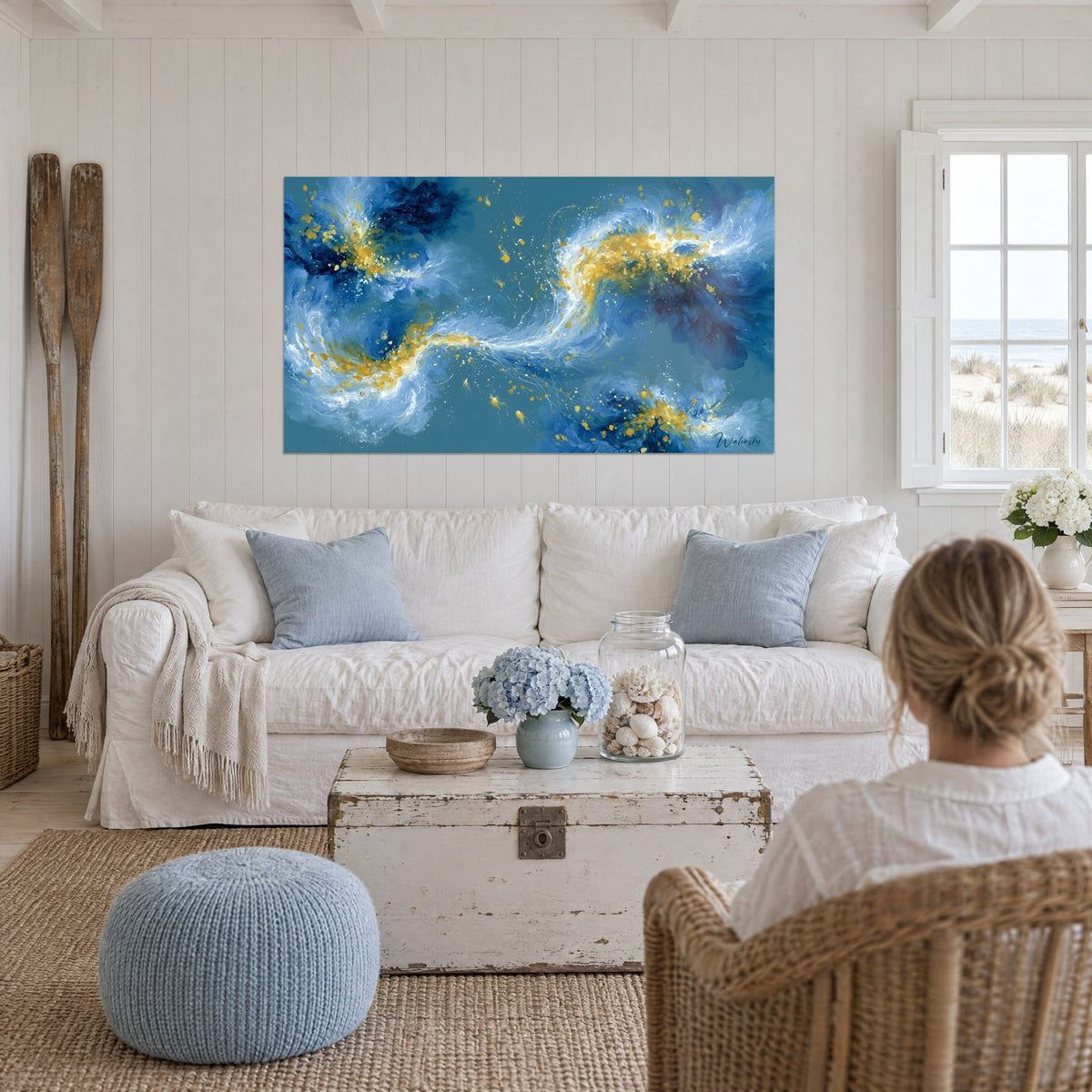 Tableau tourbillon de vagues bleu roi et or éclaboussé sur fond sarcelle, au-dessus d'un canapé dans un salon lumineux