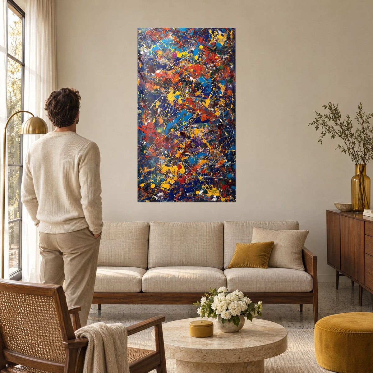 Wall art with cobalt blue and mustard yellow paint splashes, orange streaks, man seen from behind, above a sofa in a bright living room