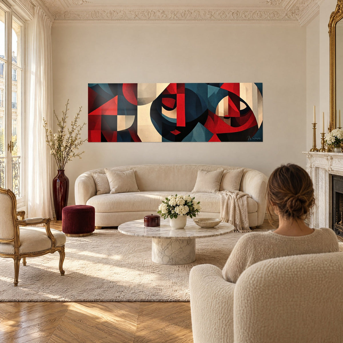 Cuadro mosaico cubista en rojo y azul petróleo con rostros estilizados, sobre un sofá en un salón luminoso