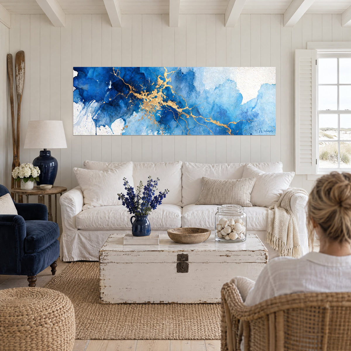 Tableau veines dorées sur marbre bleu cobalt et blanc, deux personnes de dos, au-dessus d'un canapé dans un salon lumineux