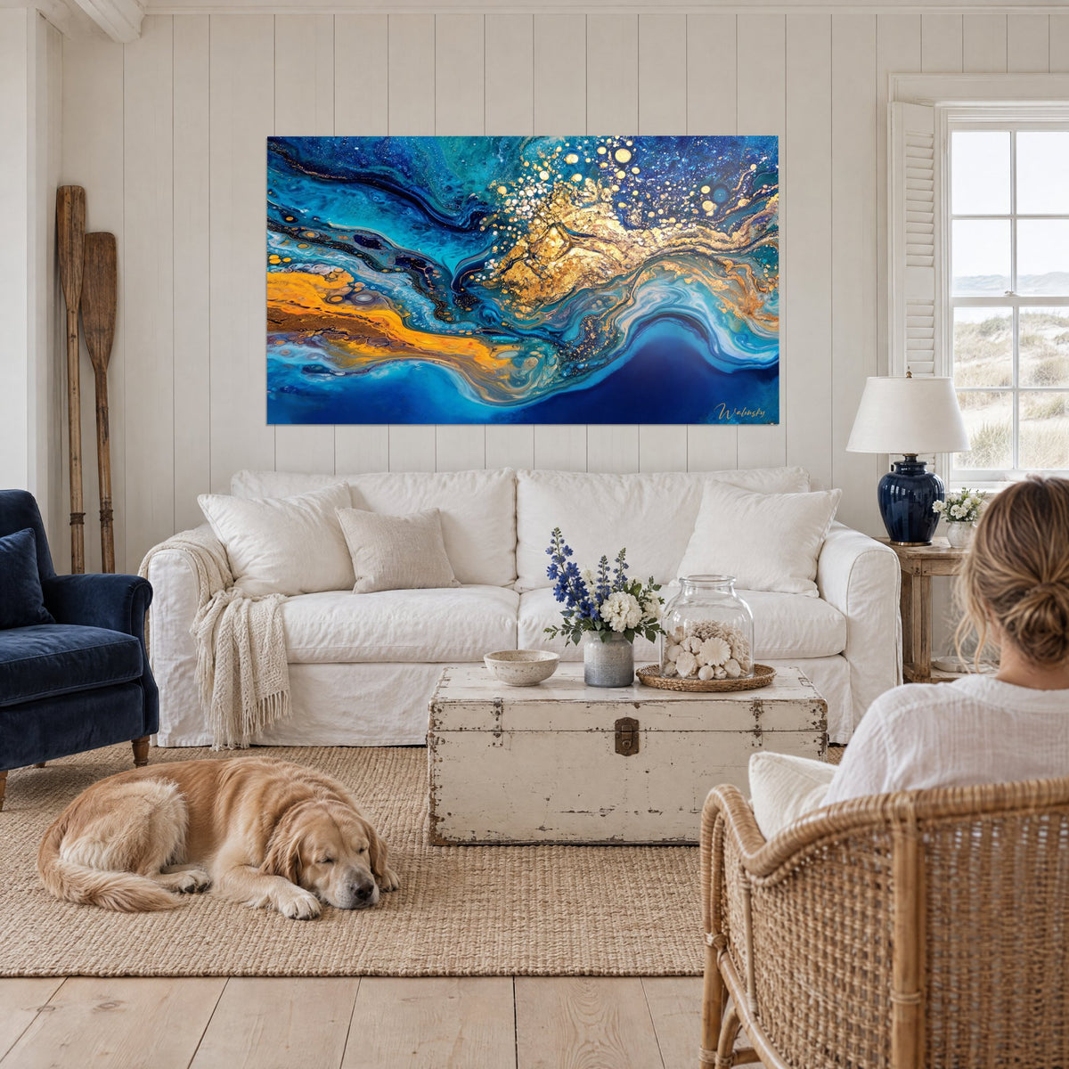Tableau marbrure bleu cobalt et pépites d'or éclaboussées, retriever couché, au-dessus d'un canapé dans un salon lumineux