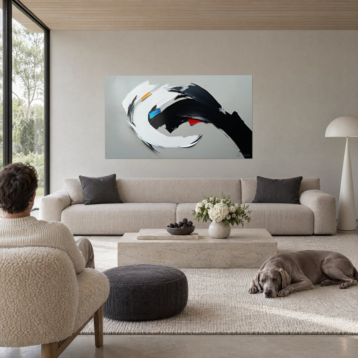 Tableau coup de pinceau blanc en spirale croisé d'un trait noir, touches bleue et rouge, au-dessus d'un canapé dans un salon lumineux