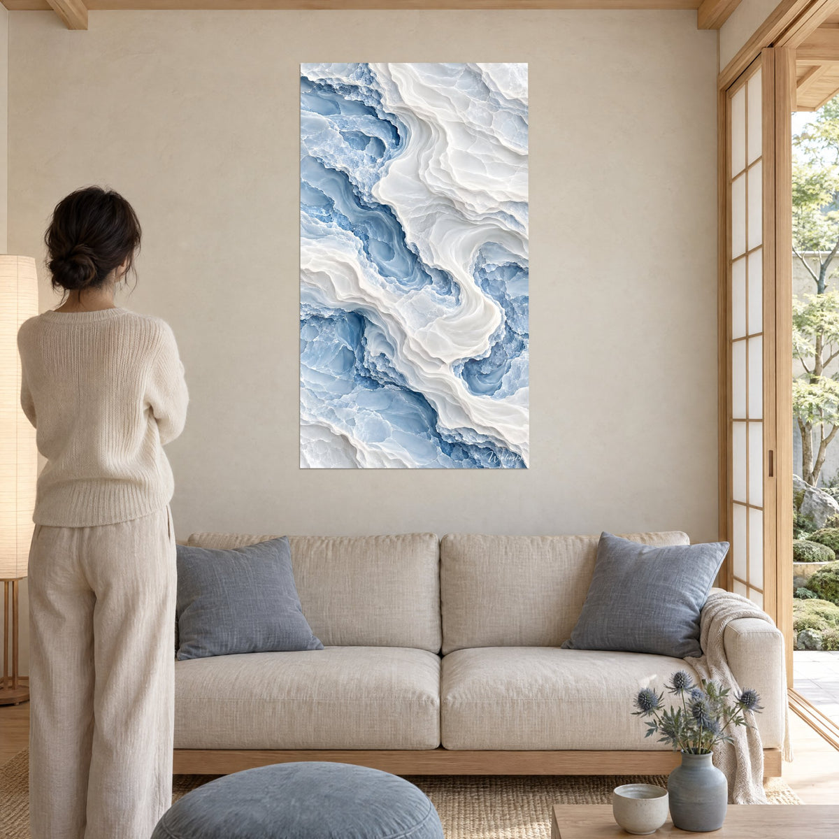 Tableau marbre sculpté aux volutes bleu glacier et blanc crème, femme de dos, au-dessus d'un canapé dans un salon lumineux