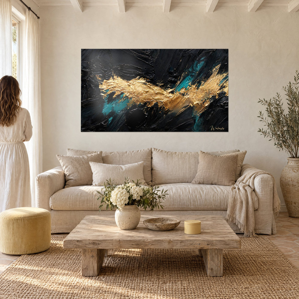 Tableau coulée d'or épaisse sur fond noir charbon et éclats turquoise, femme de dos, au-dessus d'un canapé dans un salon lumineux