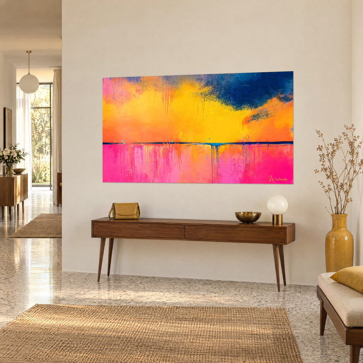 Tableau embrasement du soir en raclés orange et fuchsia, ligne sombre d'horizon, sur un mur beige près d'une console en bois