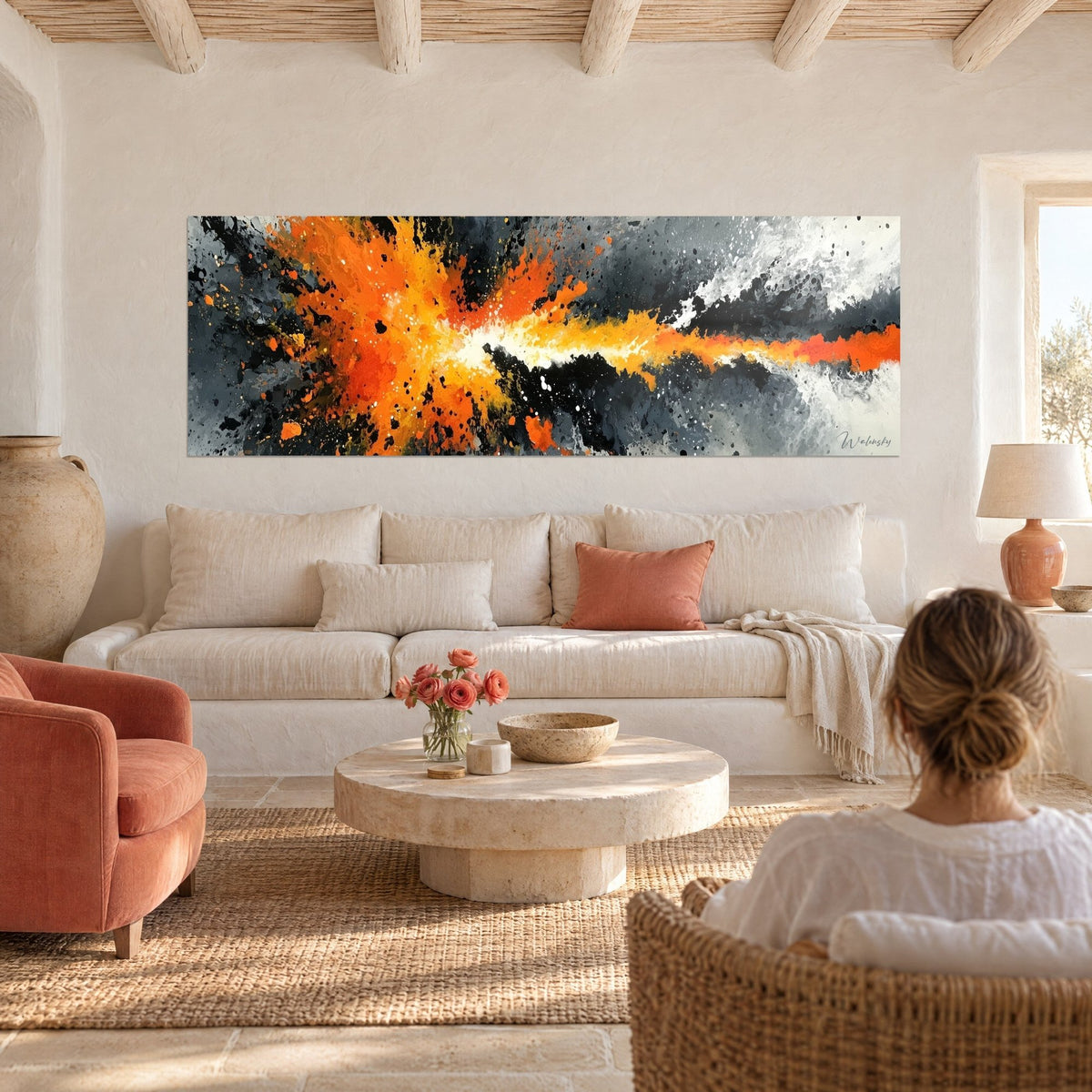 Tableau explosion orange et jaune vif sur fond gris charbon, accroché sur un mur blanc, au-dessus d'un canapé dans un salon lumineux