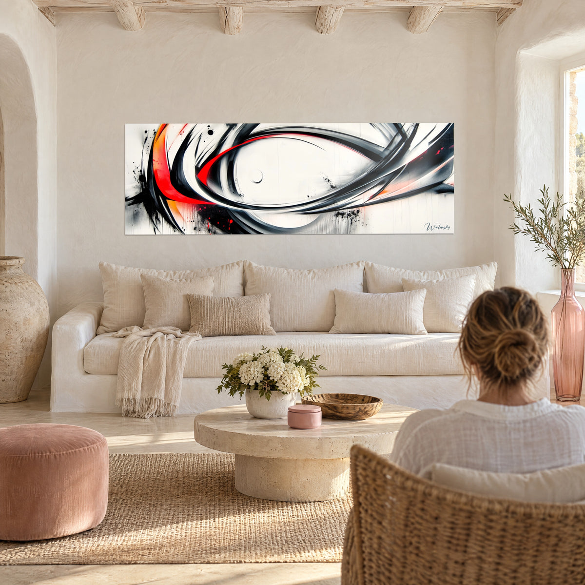 Tableau tourbillon d'encre noire et rouge vif sur fond ivoire, accroché au-dessus d'un canapé dans un salon lumineux