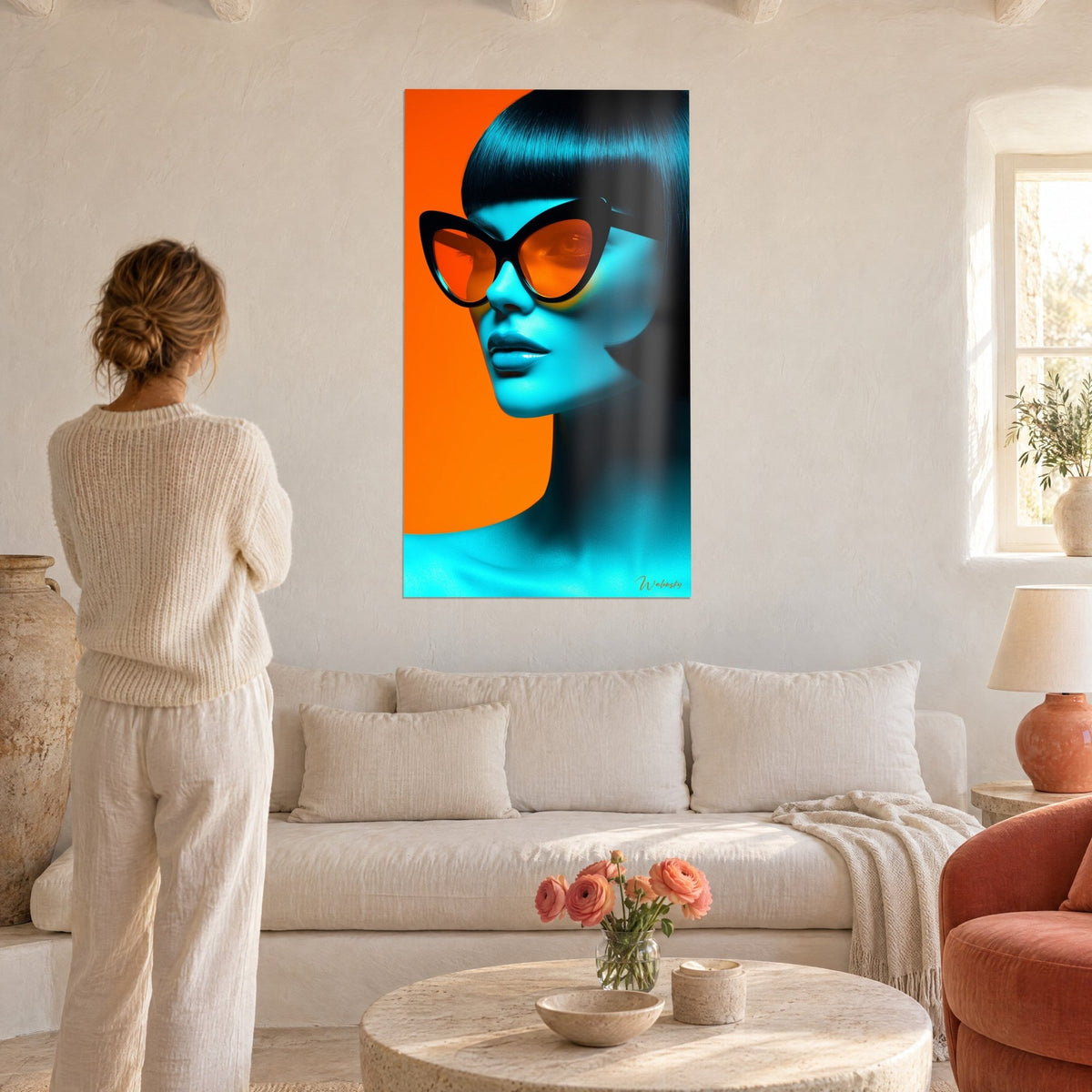 Cuadro retrato de mujer con rostro turquesa y gafas mariposa naranjas, fondo naranja vivo, mujer de espaldas sobre un sofá en un salón luminoso