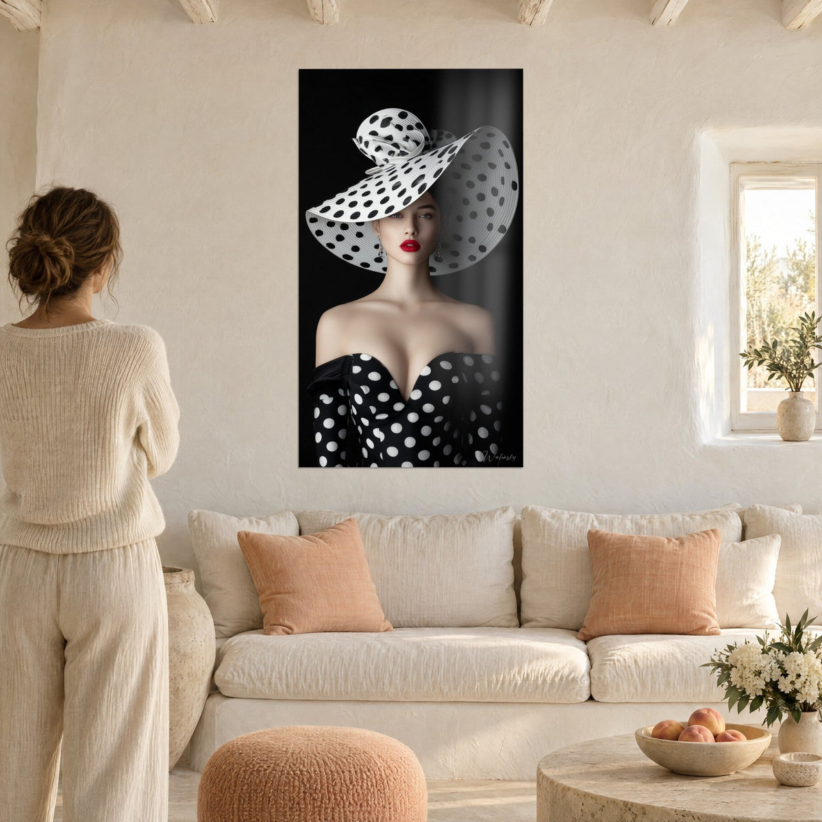 Tableau diva au chapeau blanc à pois noirs et lèvres rouges, robe bustier noire, fond sombre, au-dessus d'un canapé dans un salon lumineux