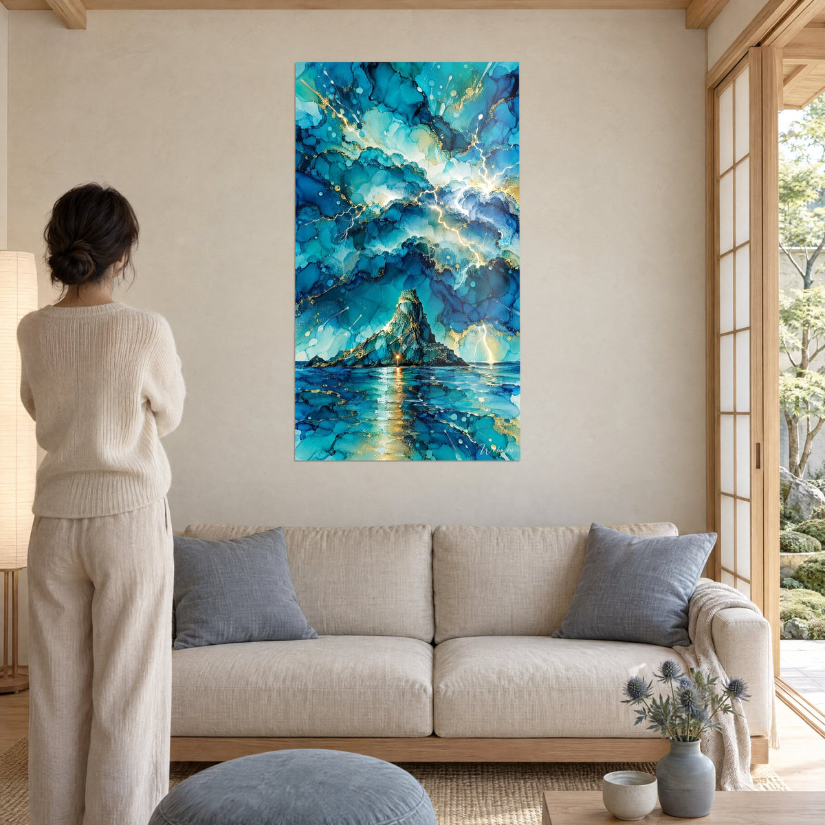Tableau rocher escarpé sous orage turquoise, éclairs dorés et phare lumineux, femme de dos, au-dessus d'un canapé dans un salon lumineux