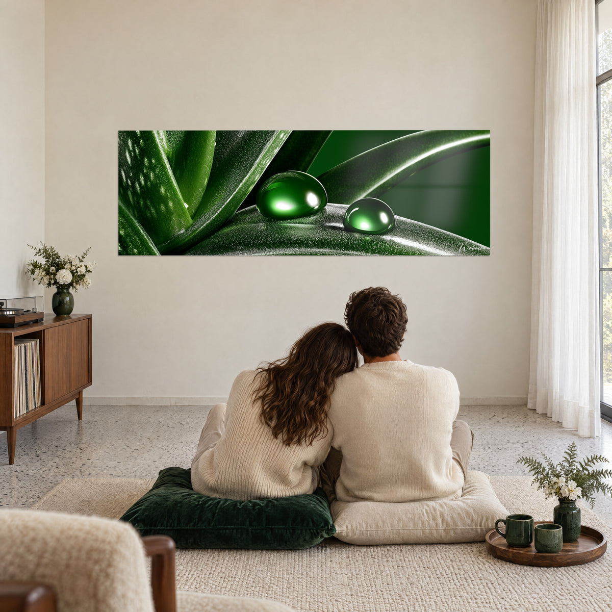 Tableau feuilles succulentes noir et vert profond, deux perles brillantes, couple de dos assis sur un coussin vert dans un salon épuré