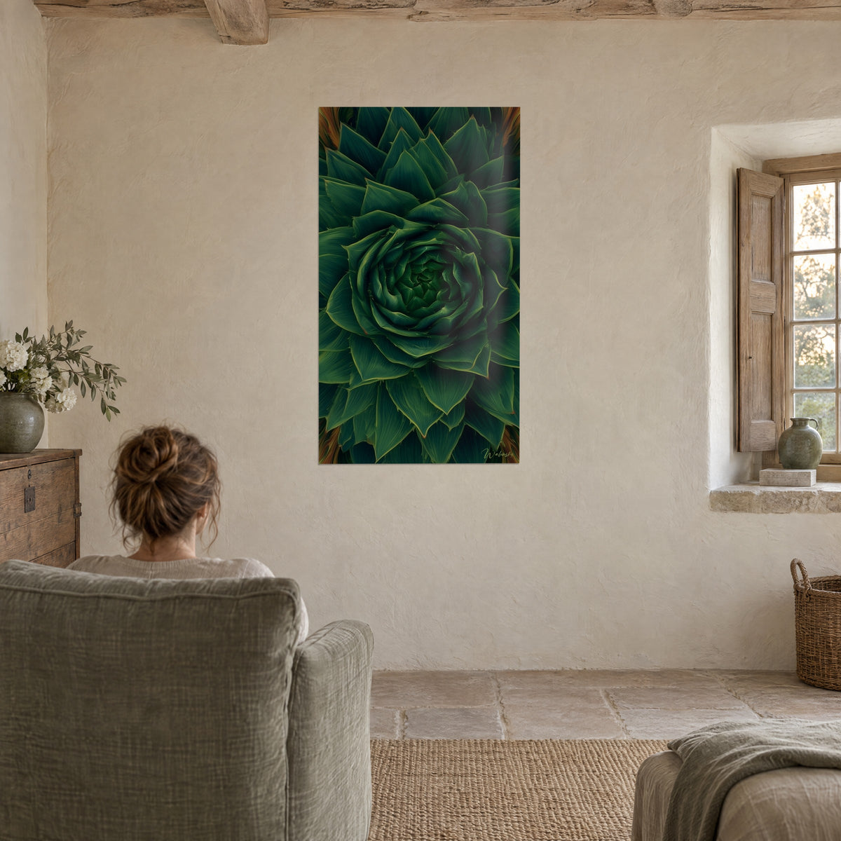 Tableau rosée de feuilles pointues vert profond et cuivre, femme de dos dans un fauteuil, salon en pierre claire