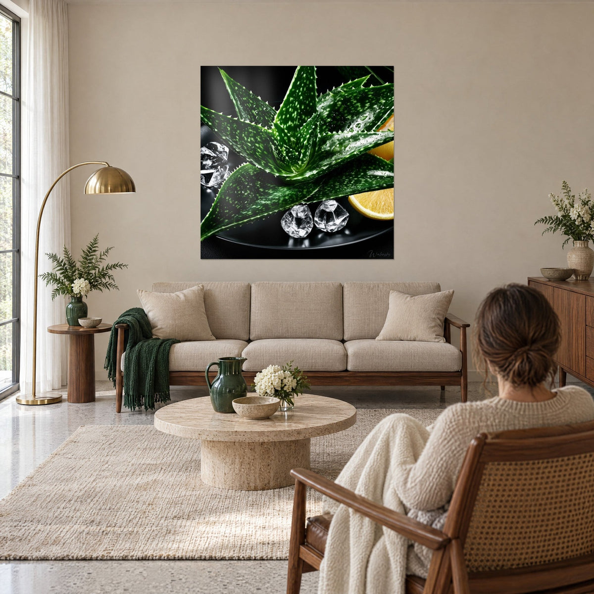 Tableau aloès aux feuilles vertes tachetées de blanc, glaçons et citron sur fond noir, au-dessus d'un canapé dans un salon lumineux
