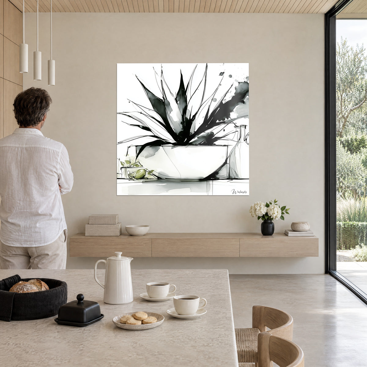 Tableau aloès graphique aux éclaboussures noires, vase blanc et olive verte, devant un homme en chemise blanche, baie vitrée boisée