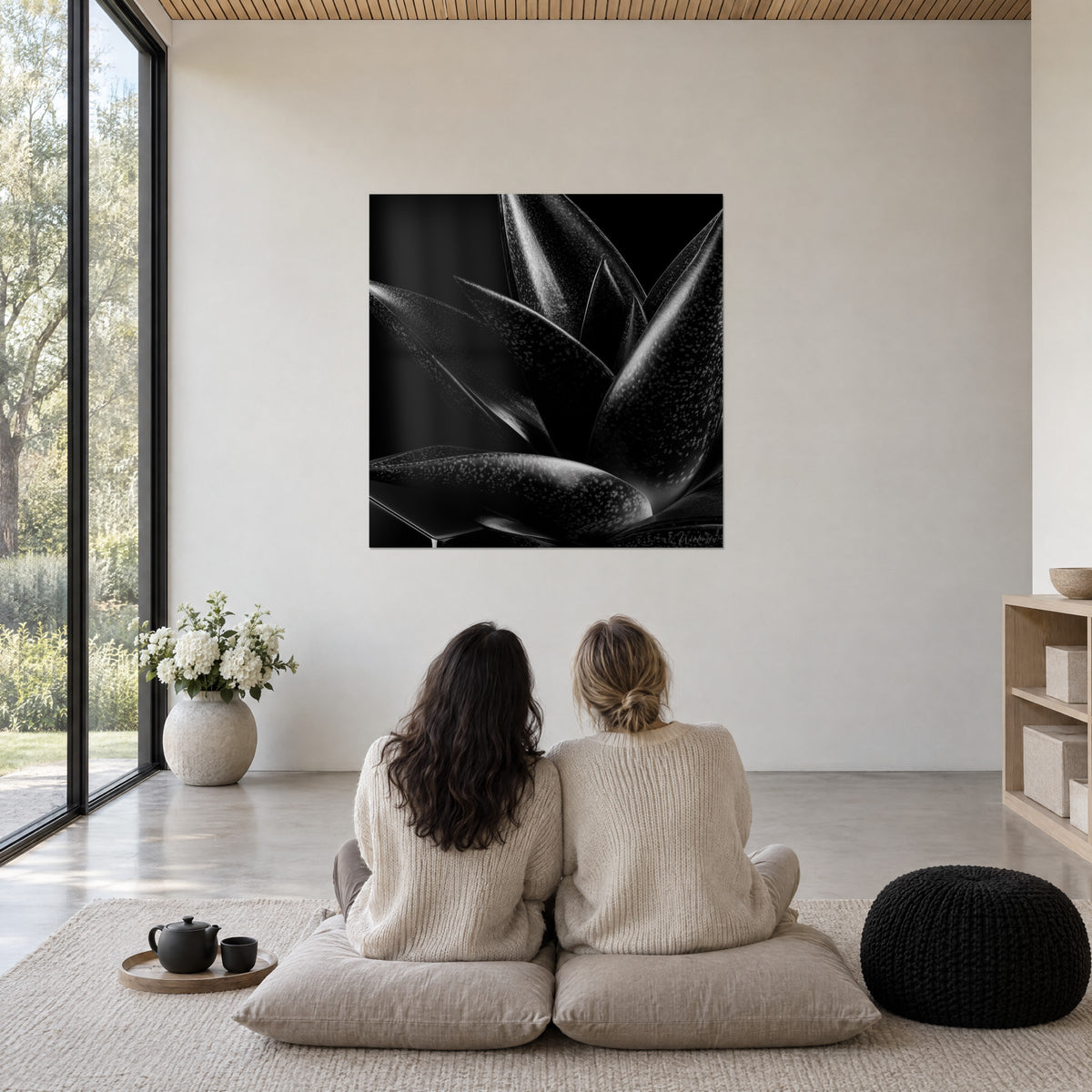 Tableau éclosion d'agave obscure, feuilles noir de jais ponctuées de gris argenté, deux personnes assises face au mur blanc