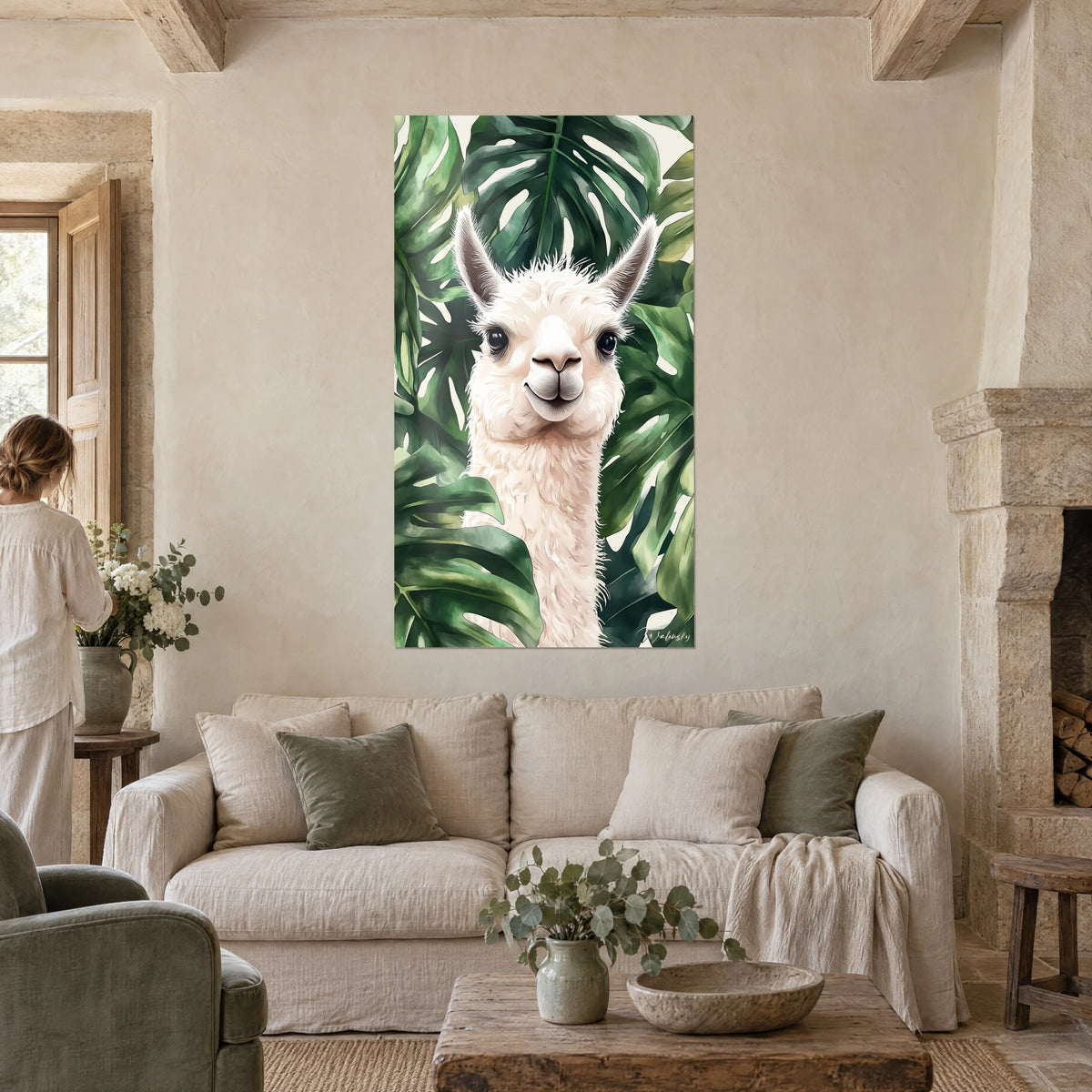 Cuadro de alpaca blanca crema con mirada oscura, rodeada de hojas de monstera verde intenso, sobre un sofá en un salón luminoso