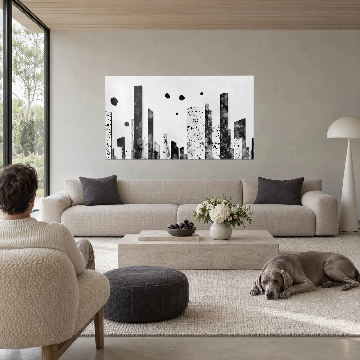 Wall art skyscrapers in black ink on white background, speckled towers and black circles, two viewers, above a sofa in a bright living room