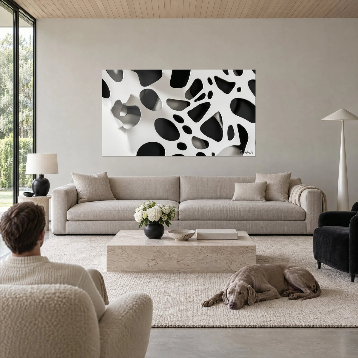 Tableau motif tacheté noir et blanc, alvéoles ovales aux ombres grises, deux personnes de dos, Weimaraner couché, au-dessus d'un canapé dans un salon lumineux