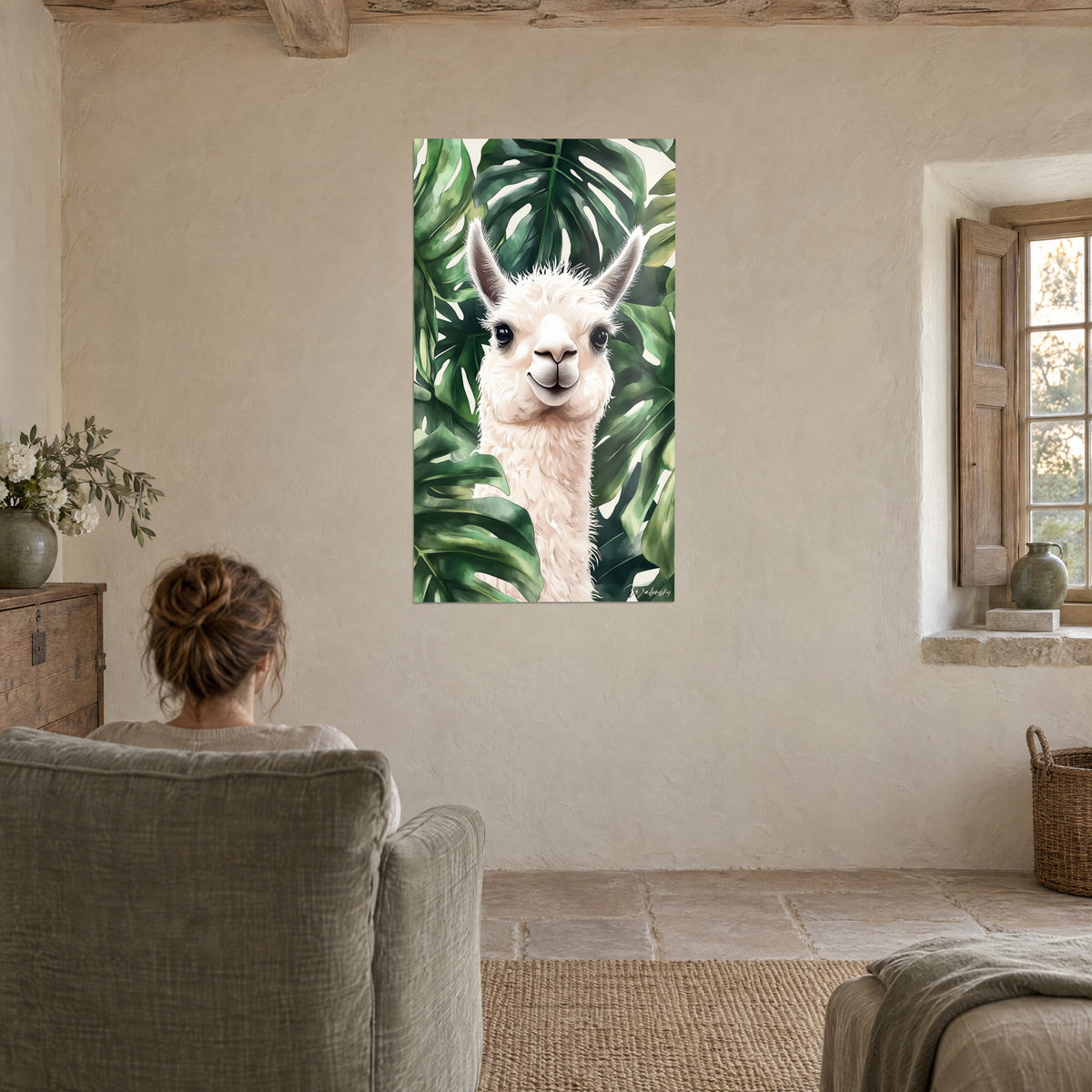 Cuadro de alpaca sonriente de lana blanca, marco de monstera verde oscuro, pared de yeso beige, sillón gris y ventana de piedra