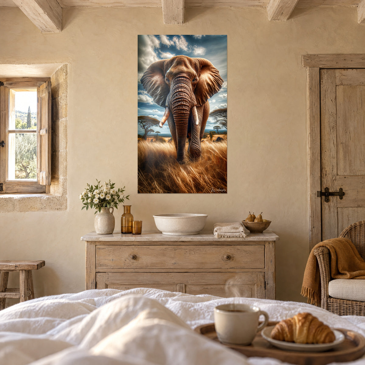 Schilderij van een olifant die ons aankijkt, oren uitgespreid tegen een blauwe en witte lucht, vaalgeel gras, boven een bed in een lichte slaapkamer