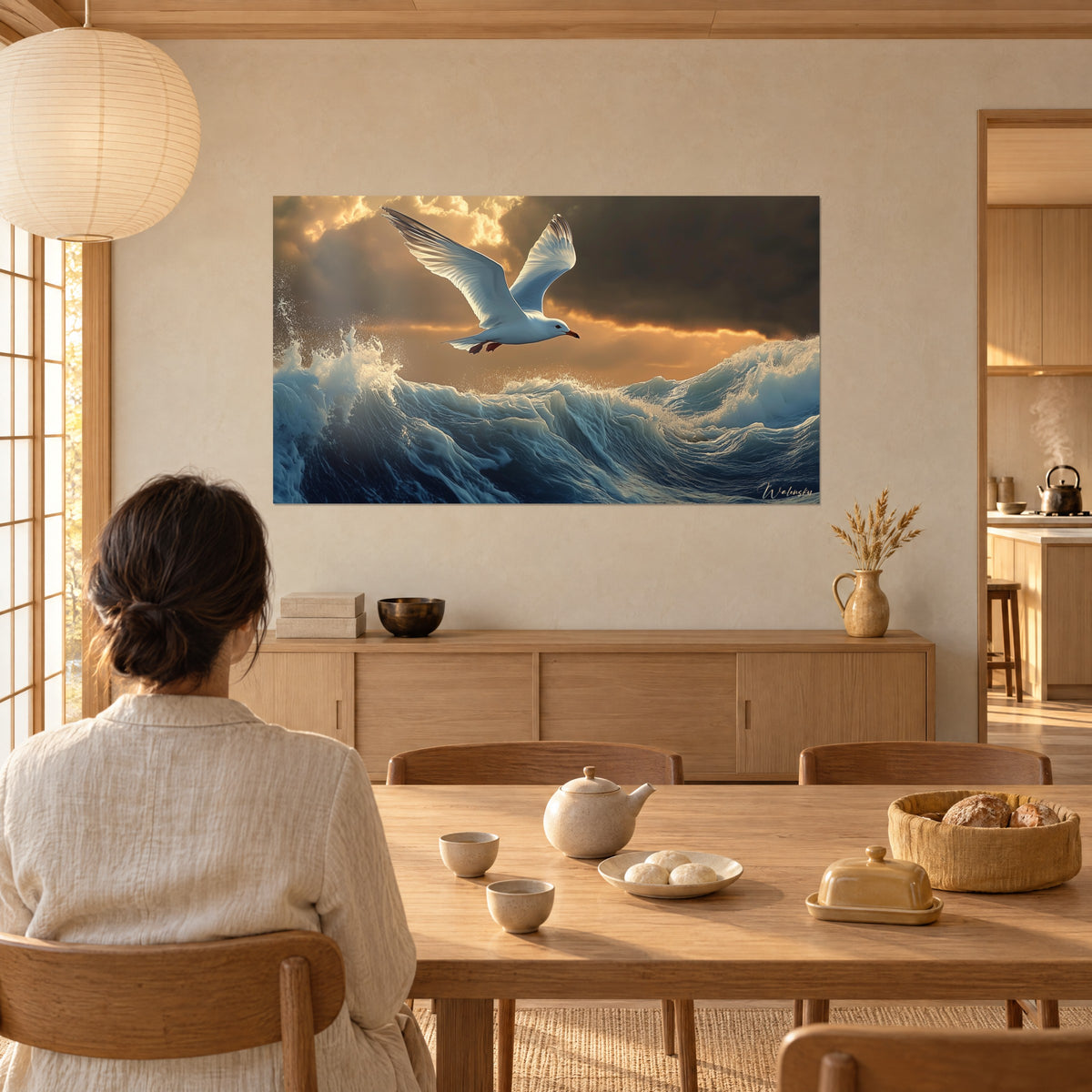 Schilderij zeevogel met wijd open vleugels, koraalroze snavel, marineblauwe golf en oranje lucht, een vrouw met de rug naar de kijker aan de eettafel
