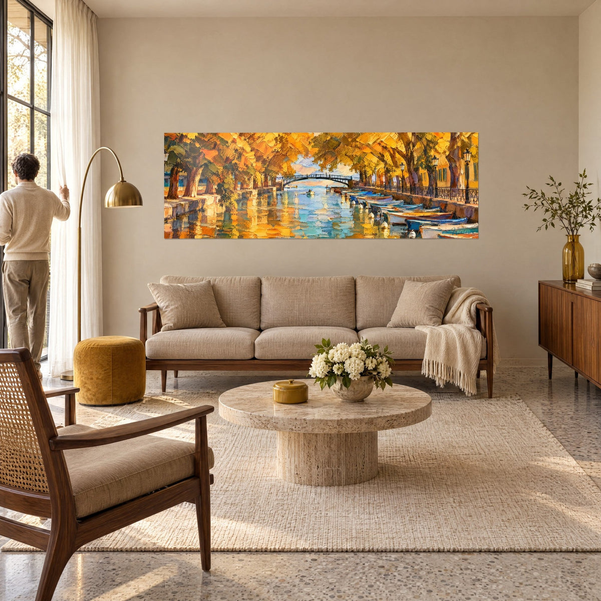 Gemälde Kanal, gesäumt von goldenen Platanen, Bogenbrücke und blauen Booten, bernsteinfarbene Spiegelungen auf dem Wasser, über einem Sofa in einem hellen Wohnzimmer