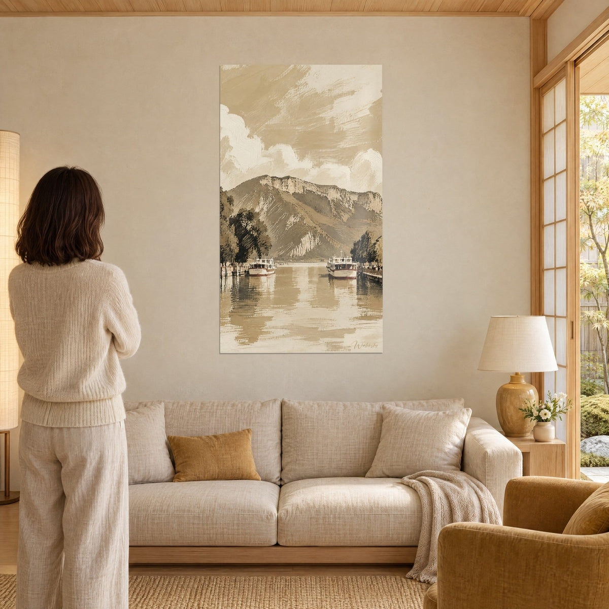 Schilderij witte boten met rode streep op sepia meer, beige rotswand, een vrouw van achteren, boven een bank in een lichte woonkamer