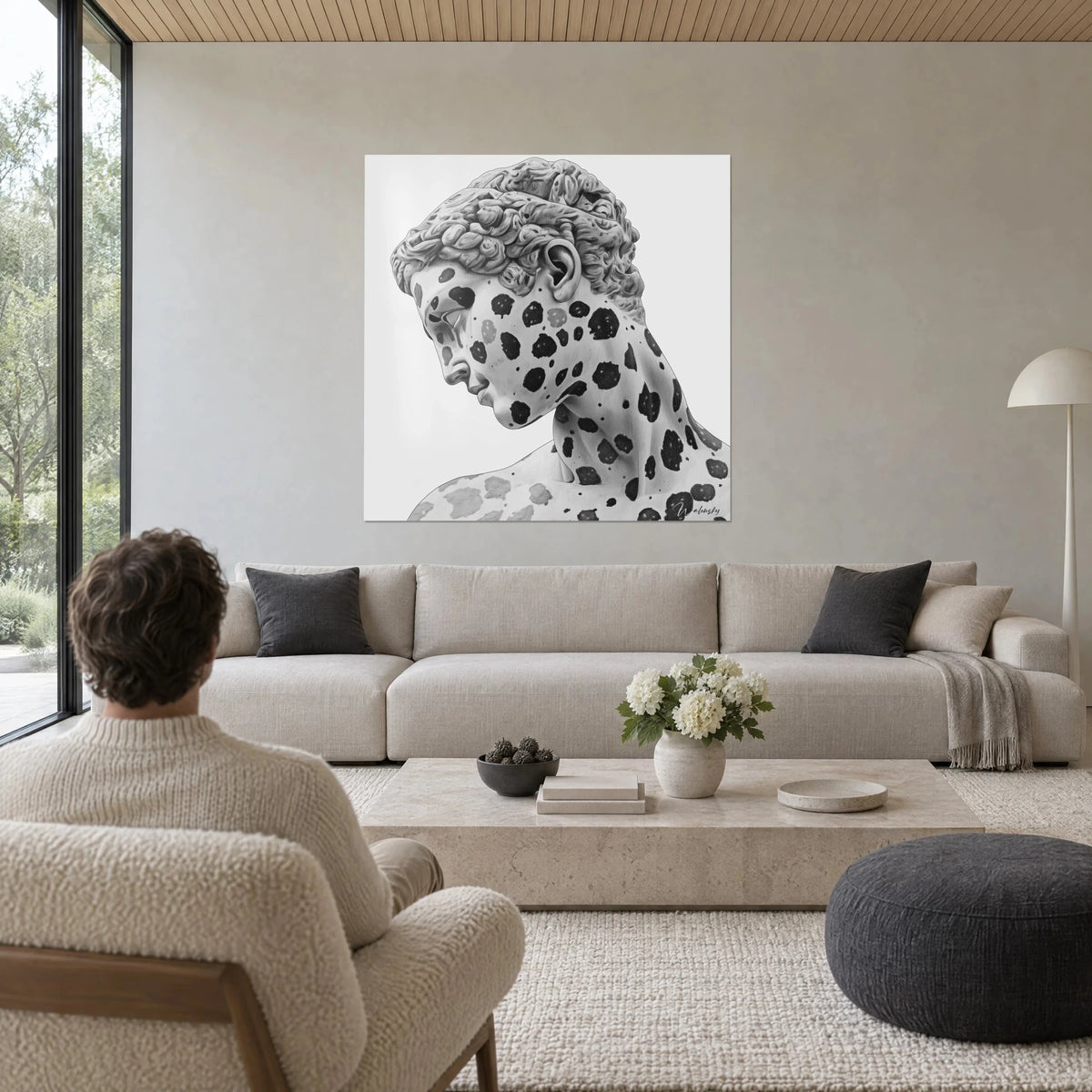 Gemälde mit antiker Büste, schwarz gefleckt, graue Locken und schattige Wange, über einem Sofa in einem hellen Wohnzimmer