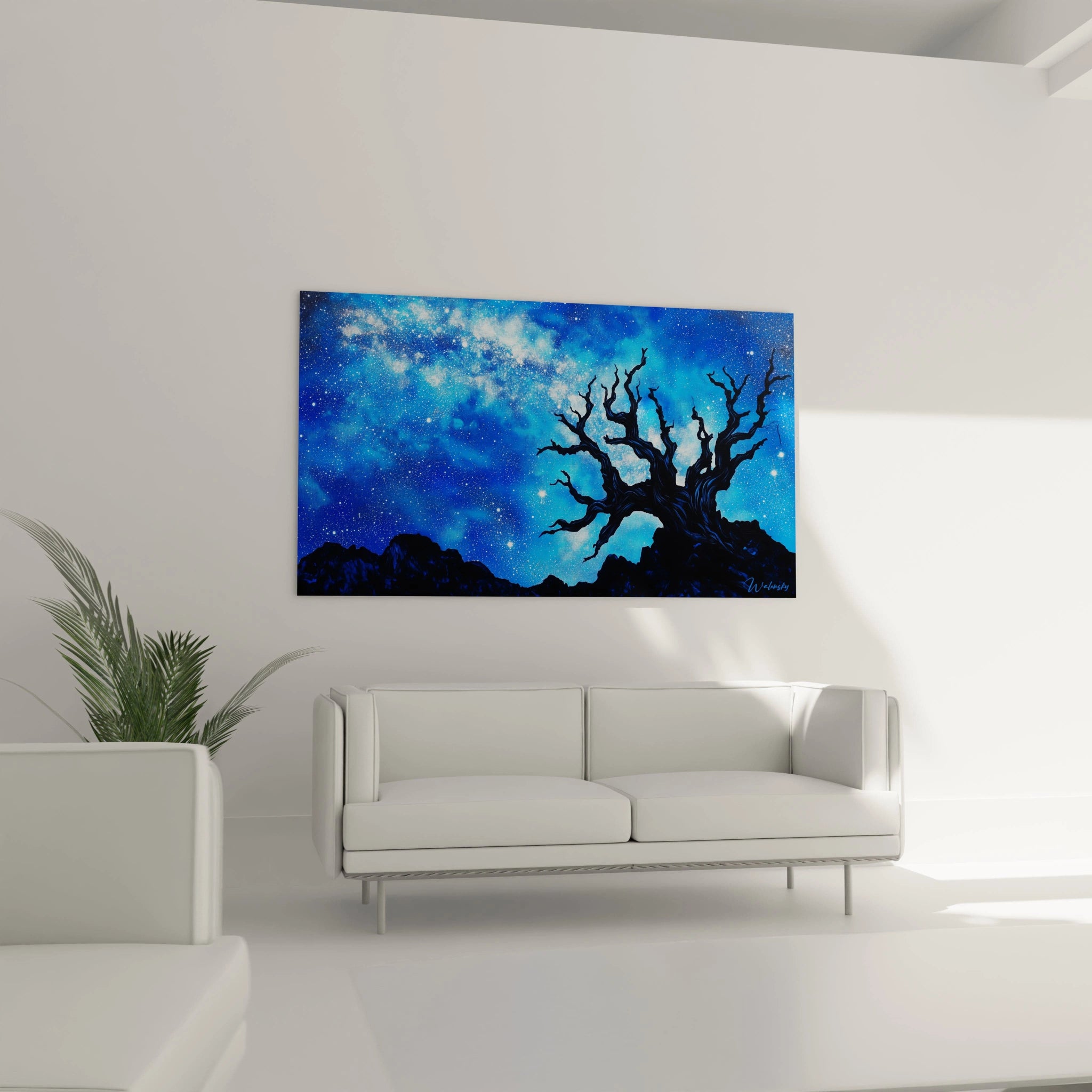 Vue d'un arbre dénudé sur un promontoire rocheux sous un ciel nocturne bleu cobalt illuminé par des milliers d'étoiles et une bande galactique blanche.
