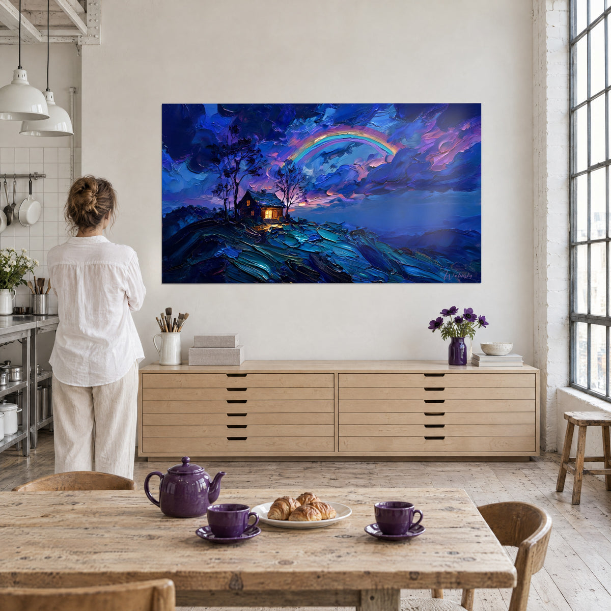 Wall art chalet with a dark roof and orange glow, blue and turquoise paint texture, hung near a wooden table with violet cups