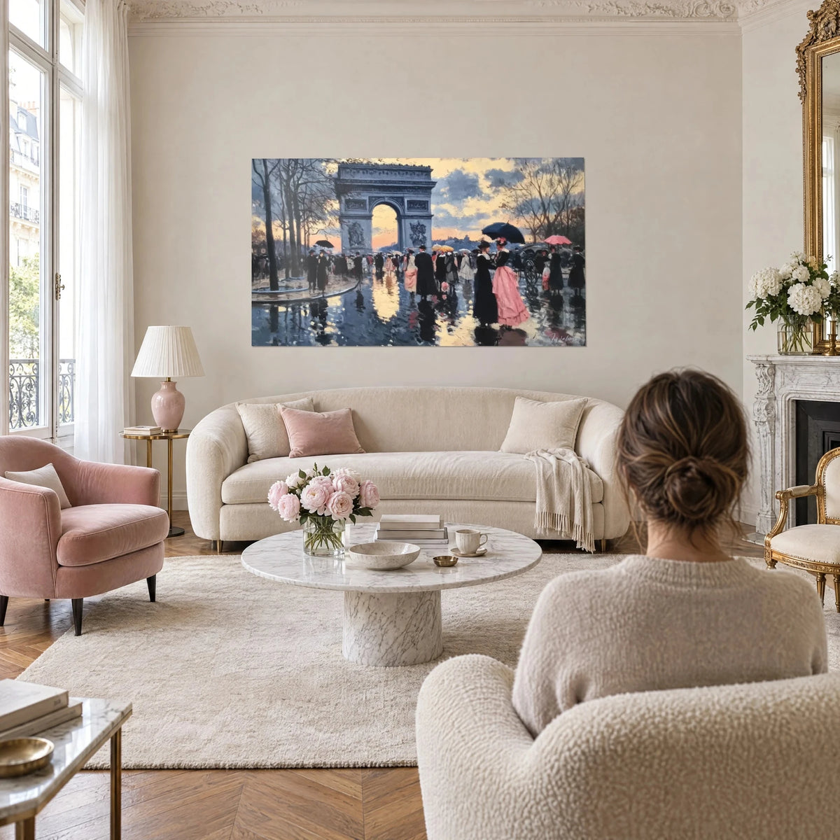 Gemälde Triumphbogen im Regen, orange-rosa Himmel, Passanten mit schwarzen Regenschirmen, Frau von hinten über einem Sofa in einem hellen Wohnzimmer