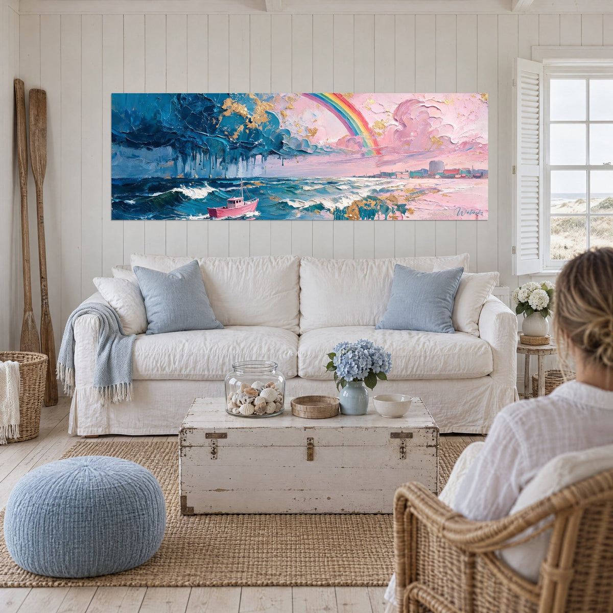 Tableau bateau de pêche rose sous un arc-en-ciel, mer bleu orage et écume blanche, au-dessus d'un canapé dans un salon lumineux