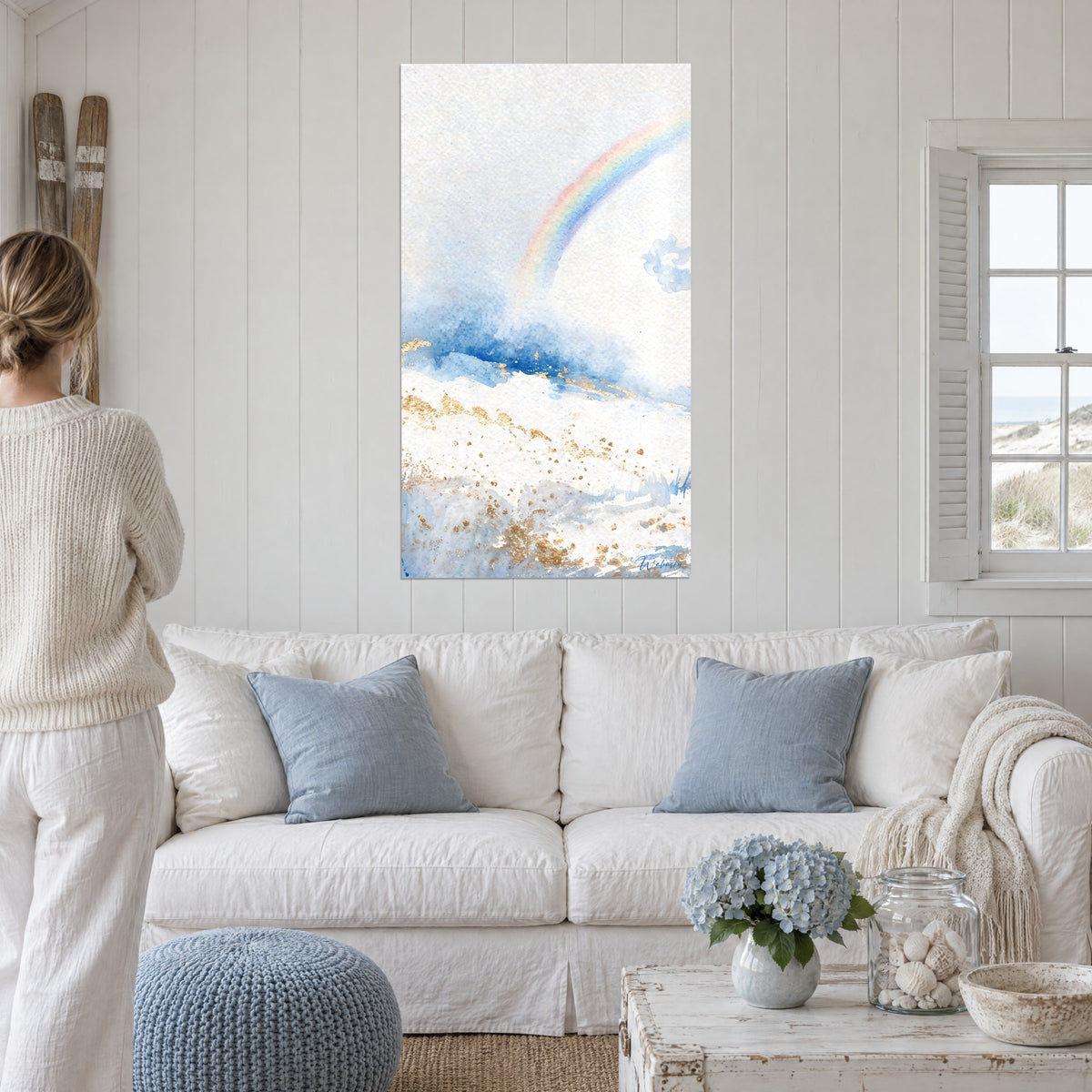 Tableau arc-en-ciel pastel jaillissant d'un nuage bleu cobalt, touches d'or, femme de dos, au-dessus d'un canapé dans un salon lumineux